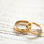 Two gold wedding bands resting on a Bible passage